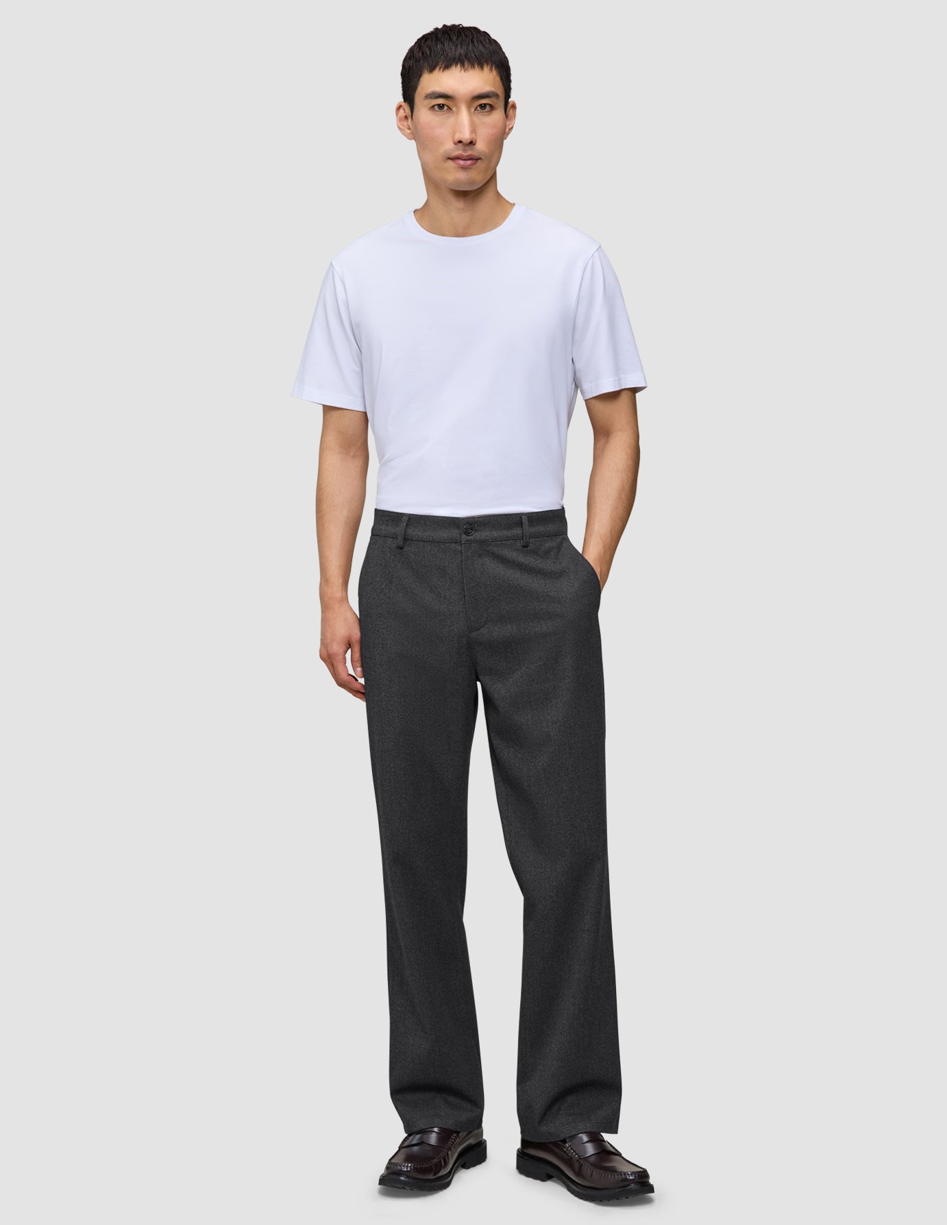 En mand har en hvid T-shirt på og mørkegrå Atelier Pants Relaxed i brudt twill.